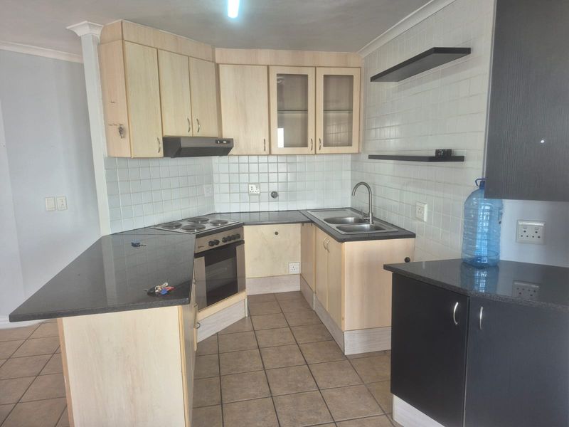 Functional kitchen featuring light wood cabinetry, granite countertops, built-in oven and hob, and tiled backsplash, offering a practical layout for daily use.