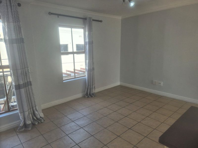 A bright, empty living room featuring neutral wall paint, ceramic floor tiles, and coved cornicing, offering a clean canvas for personalization.