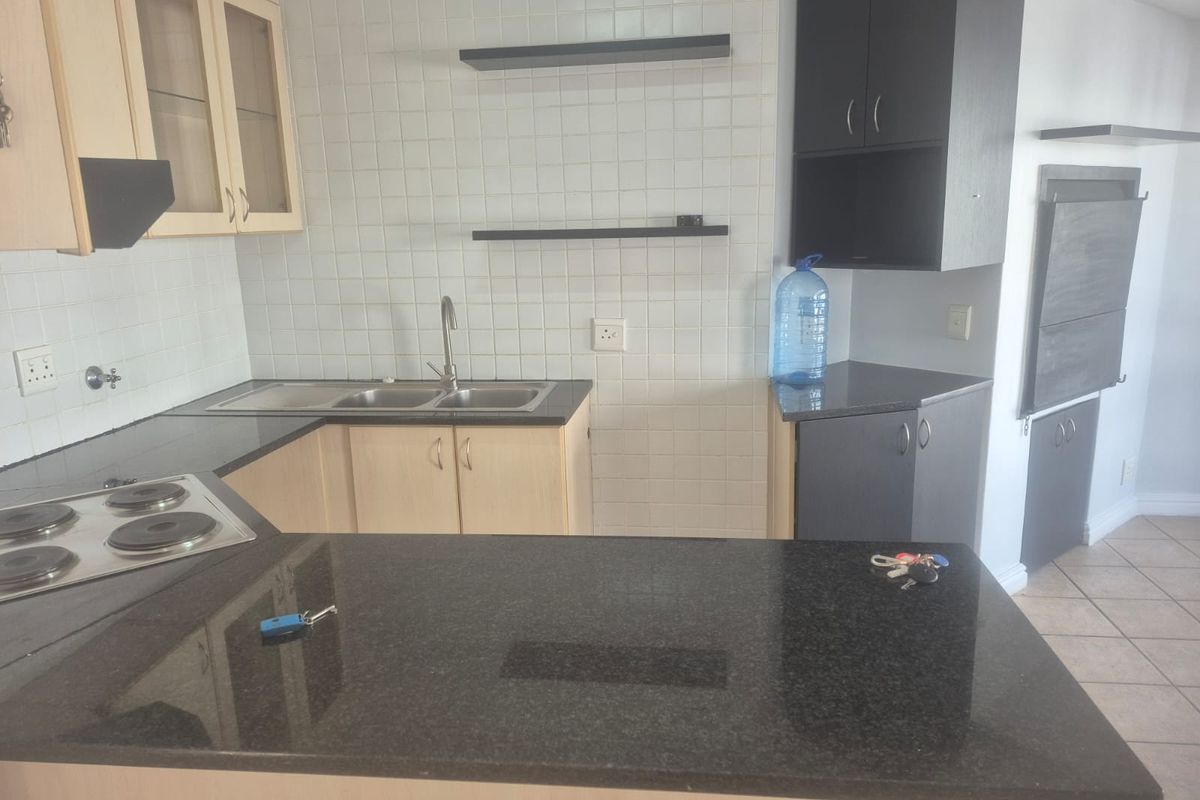 A functional kitchen featuring granite countertops, built-in cabinetry, an electric hob, and a double sink with a tiled backsplash.
