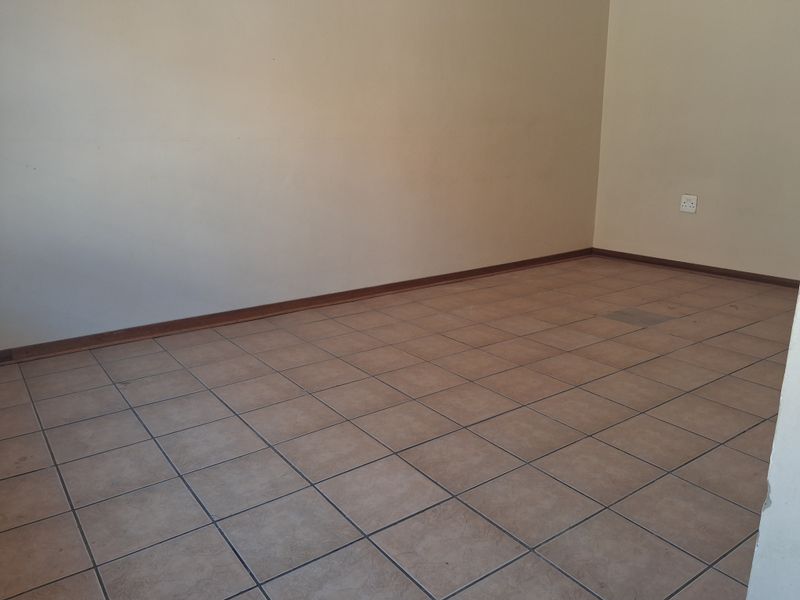 An empty living area featuring ceramic floor tiles and neutral wall paint, providing a blank canvas for interior design.