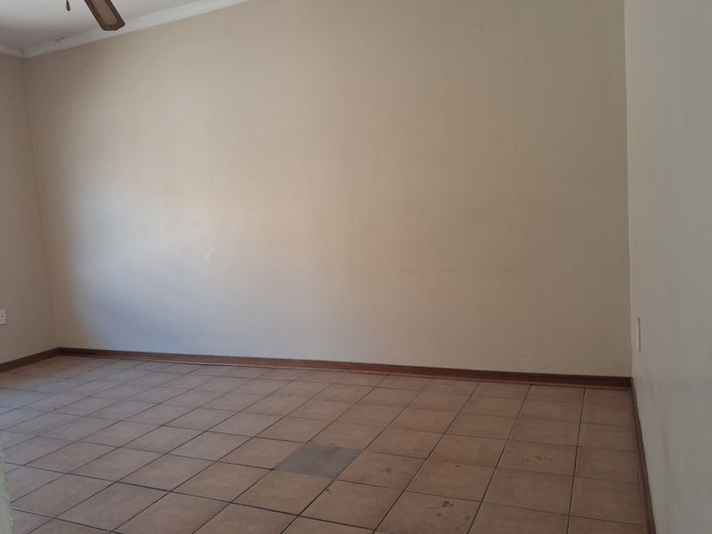 An empty living room featuring tiled flooring, a ceiling fan, and neutral wall finishes, ready for personalization.