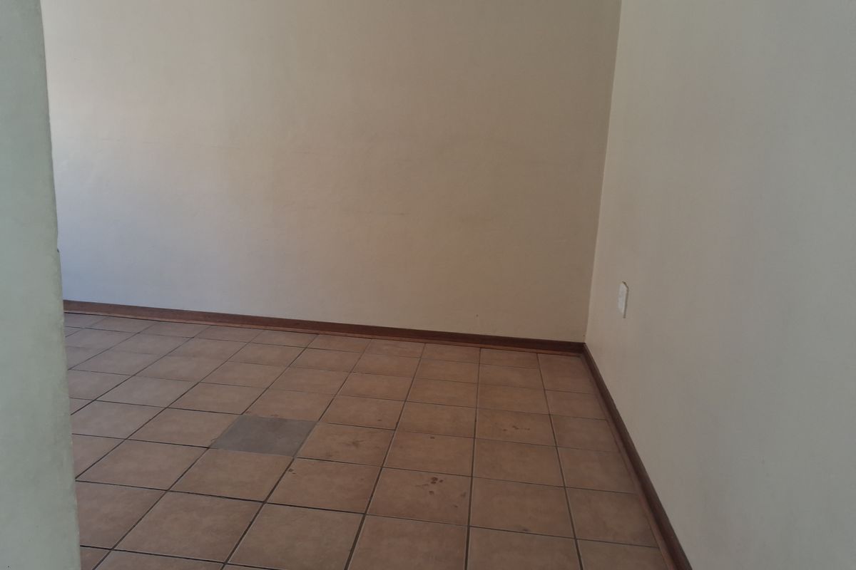 An empty living area featuring ceramic floor tiles and neutral walls, providing a blank canvas for interior design and personalization.
