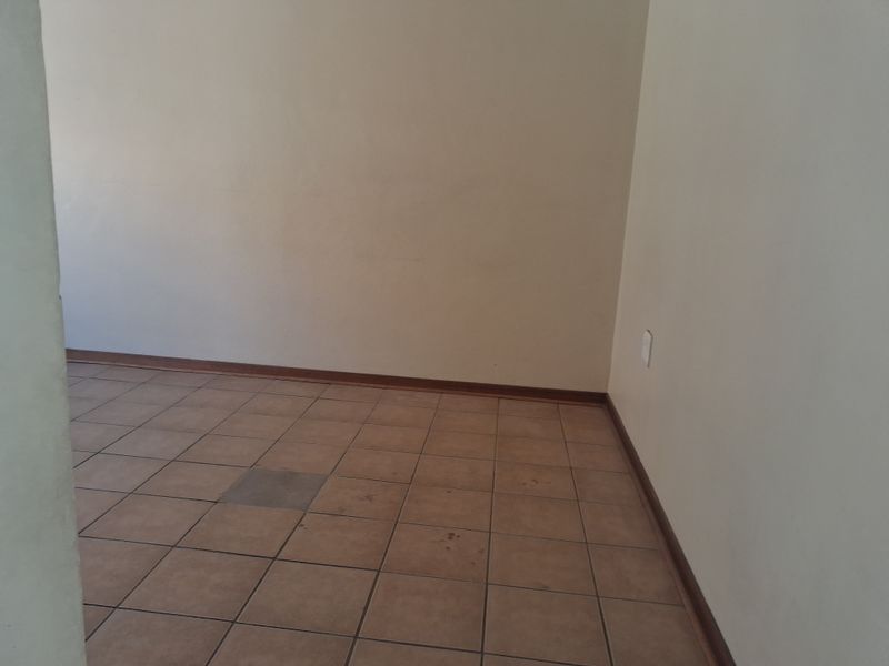 An empty living area featuring ceramic floor tiles and neutral walls, providing a blank canvas for interior design and personalization.