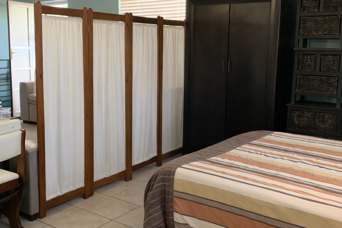 A bedroom featuring tiled flooring and neutral wall tones, currently partitioned to create a separate living area.