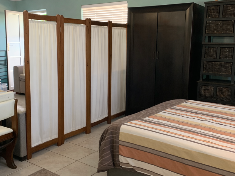 A bedroom featuring tiled flooring and neutral wall tones, currently partitioned to create a separate living area.