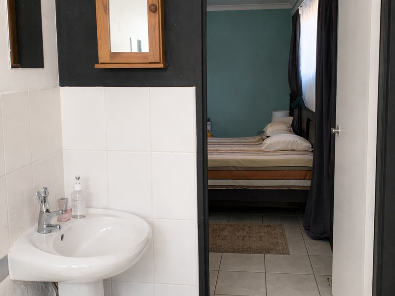 Bathroom featuring a pedestal basin and wall-mounted cabinet, with a direct view into an adjacent bedroom through an open doorway.