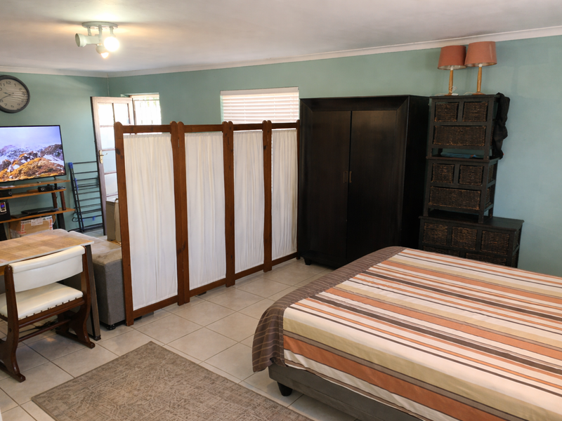 A bedroom featuring tiled flooring and a neutral wall finish, currently utilized as a multi-functional living and sleeping space.