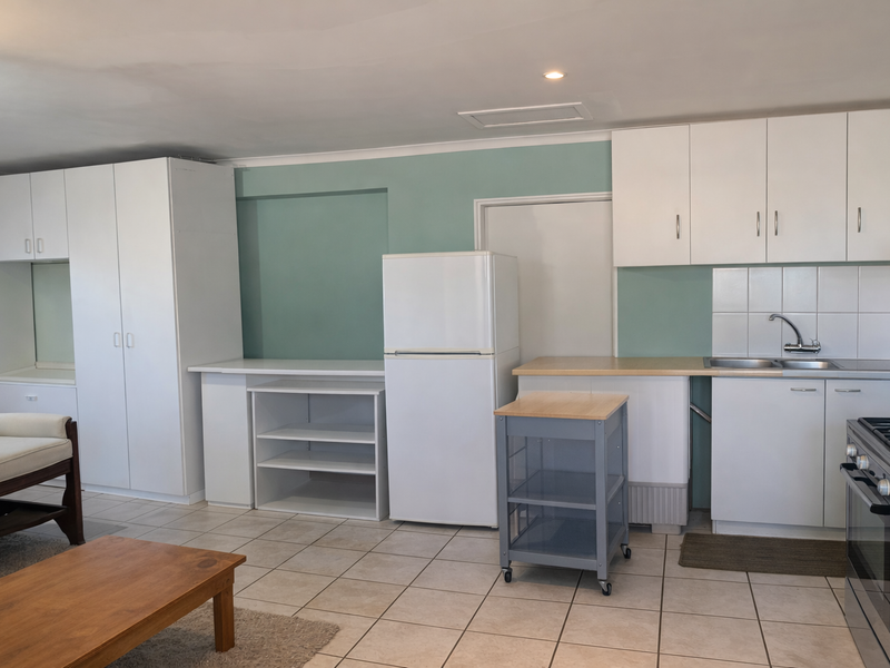 A functional kitchen area featuring white cabinetry, tiled flooring, a gas stove, and a tiled backsplash, offering a clean and practical layout.