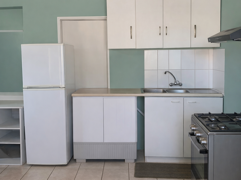 A functional kitchen featuring white cabinetry, a stainless steel sink with tiled splashback, and a gas stove with an extractor fan.