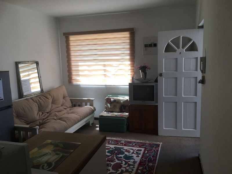 A functional living room featuring a panel door, roller blinds, and an integrated intercom system, providing a basic and practical living space.