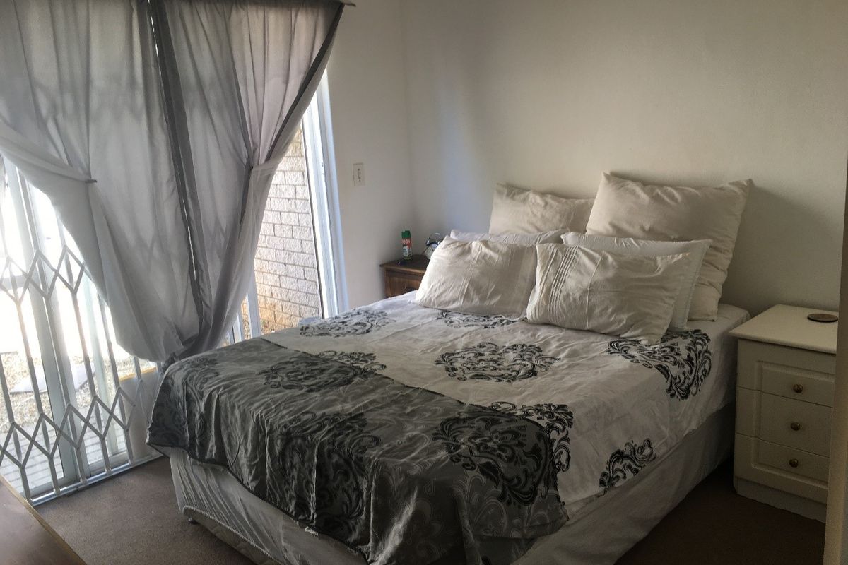 A bedroom featuring carpet flooring and a sliding glass door with an integrated security gate providing access to the exterior.
