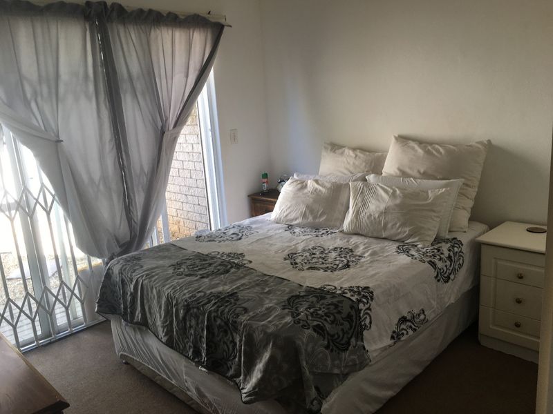 A bedroom featuring carpet flooring and a sliding glass door with an integrated security gate providing access to the exterior.