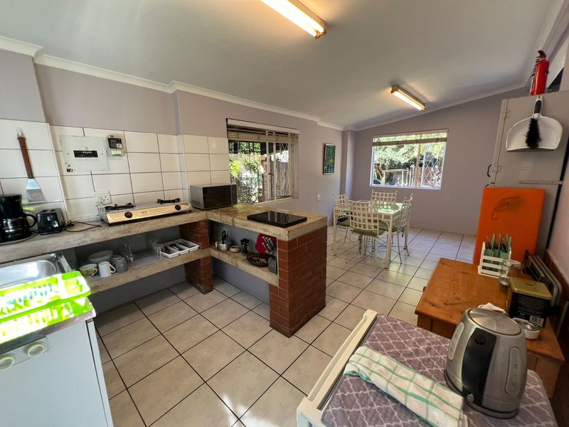 Open-plan kitchen and dining area featuring brick-built counters, tiled flooring, and functional layout with direct access to the dining space.