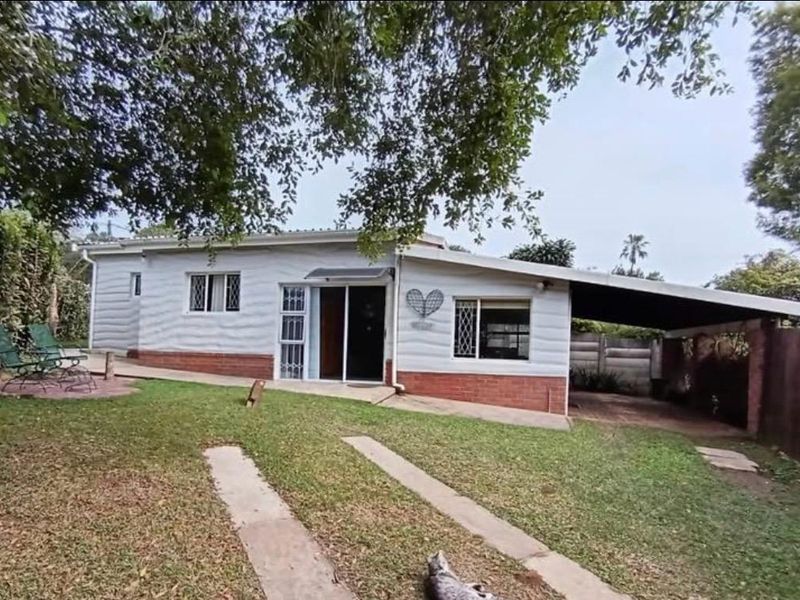 Rear view of the cottage featuring a brick base, attached carport, and sliding door access to the garden area.