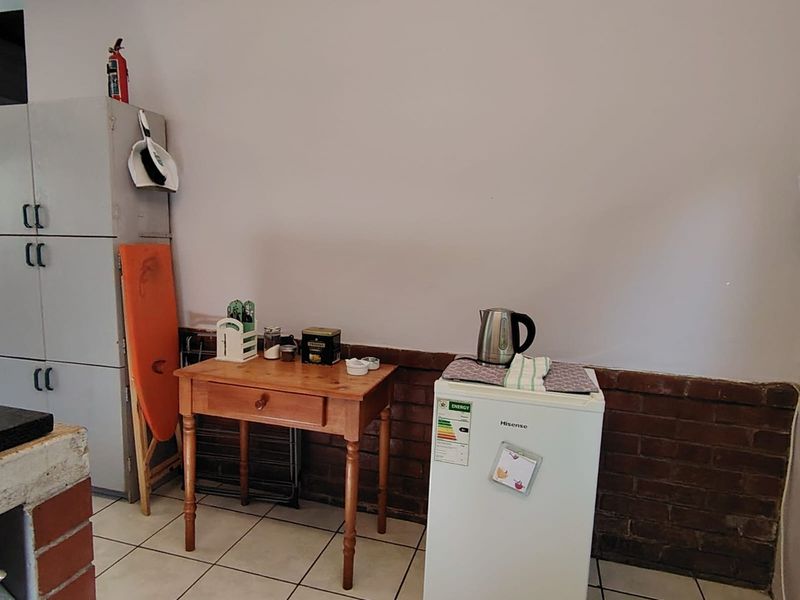 A functional kitchen area featuring tiled flooring, exposed brick wall detailing, and built-in storage cabinetry.