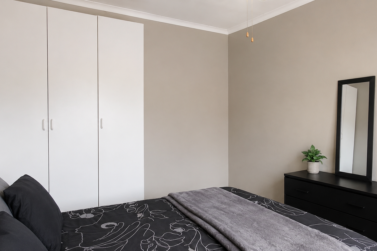 A well-maintained bedroom featuring neutral wall tones and ample built-in cupboard storage.