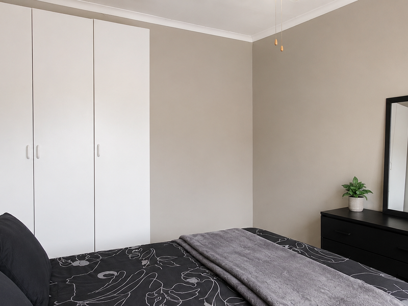 A well-maintained bedroom featuring neutral wall tones and ample built-in cupboard storage.