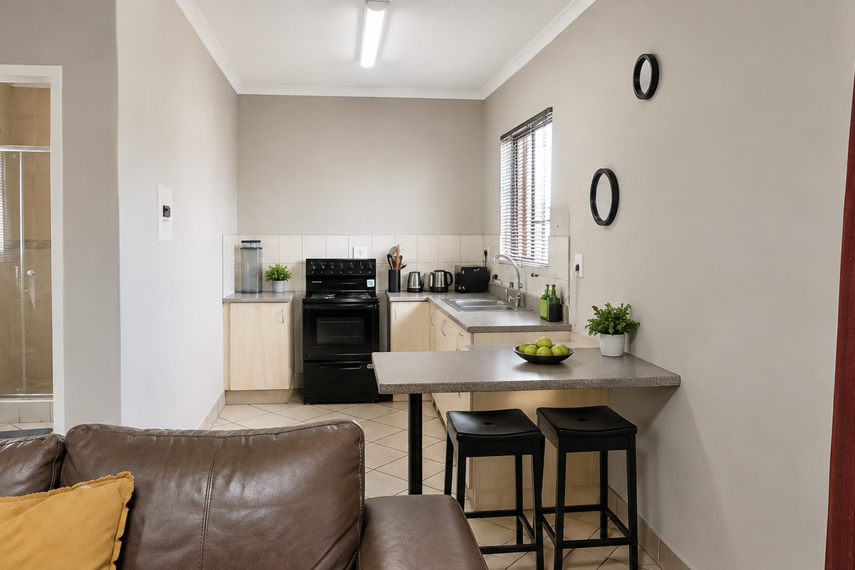 Open-plan kitchen area featuring built-in cabinetry and a breakfast counter, with an adjacent bathroom visible through the doorway.