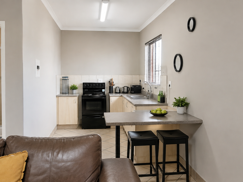 Open-plan kitchen area featuring built-in cabinetry and a breakfast counter, with an adjacent bathroom visible through the doorway.