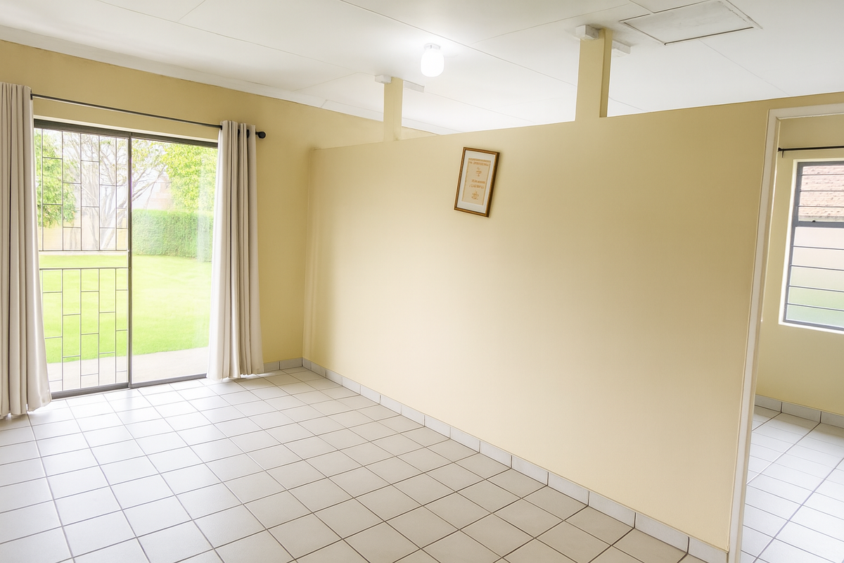 An empty living area featuring tiled flooring, a sliding glass door with security gate, and a partial room divider.