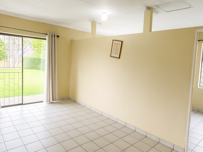 An empty living area featuring tiled flooring, a sliding glass door with security gate, and a partial room divider.