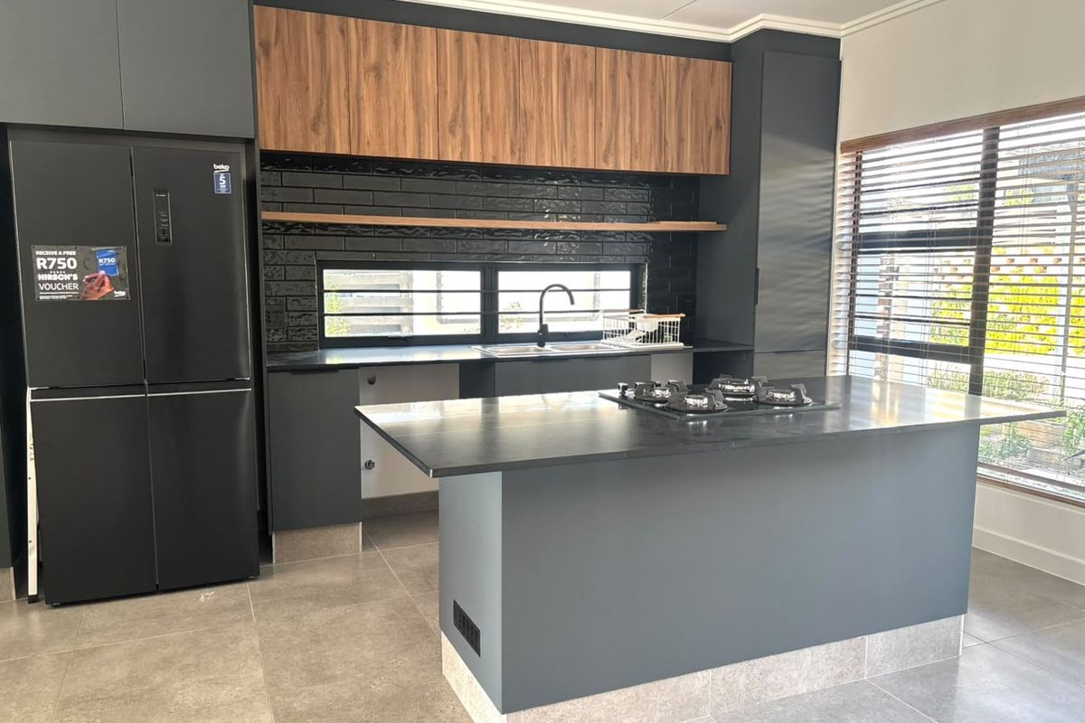 Modern kitchen featuring dark cabinetry, a central island with a gas hob, tiled splashback, and high-quality finishes throughout.