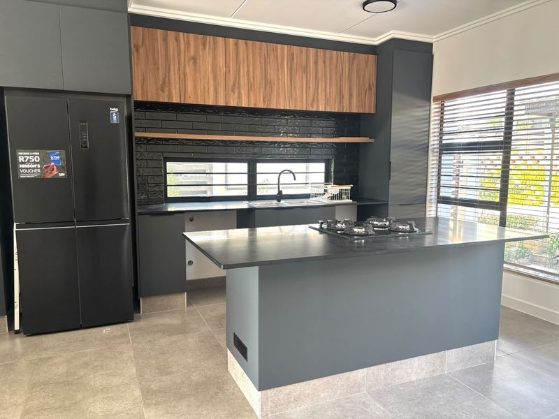 Modern kitchen featuring dark cabinetry, a central island with a gas hob, tiled splashback, and high-quality finishes throughout.