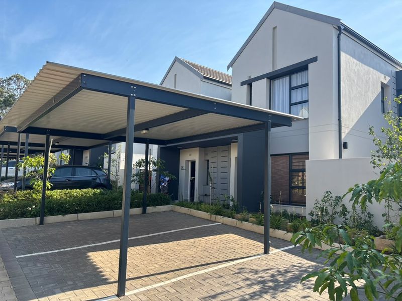 Modern townhouse exterior featuring a covered carport, paved driveway, and contemporary architectural design with clean lines and neutral finishes.