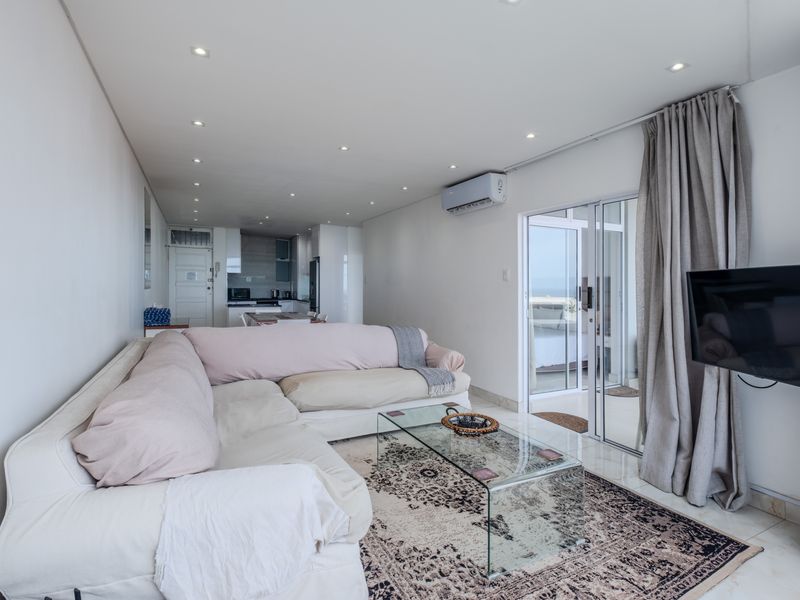 Open-plan living area featuring tiled floors, recessed lighting, and a split-system air conditioner, with direct access to a balcony through sliding glass doors.