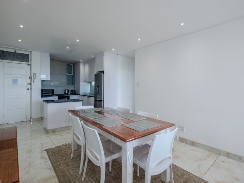 Open-plan living and dining area featuring modern kitchen cabinetry, stone countertops, and polished marble-look floor tiles throughout.