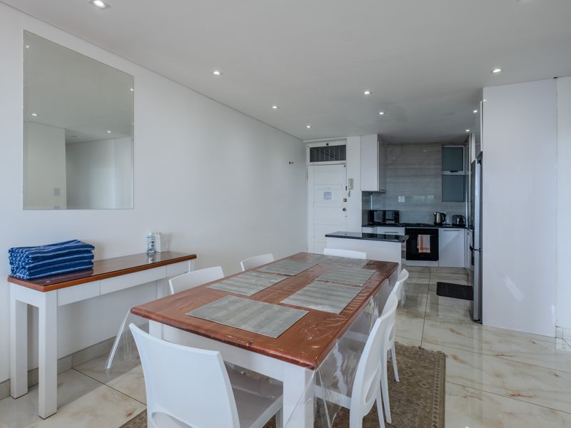 An open-plan living and dining area featuring tiled floors, recessed lighting, and a functional kitchen with granite countertops and built-in appliances.