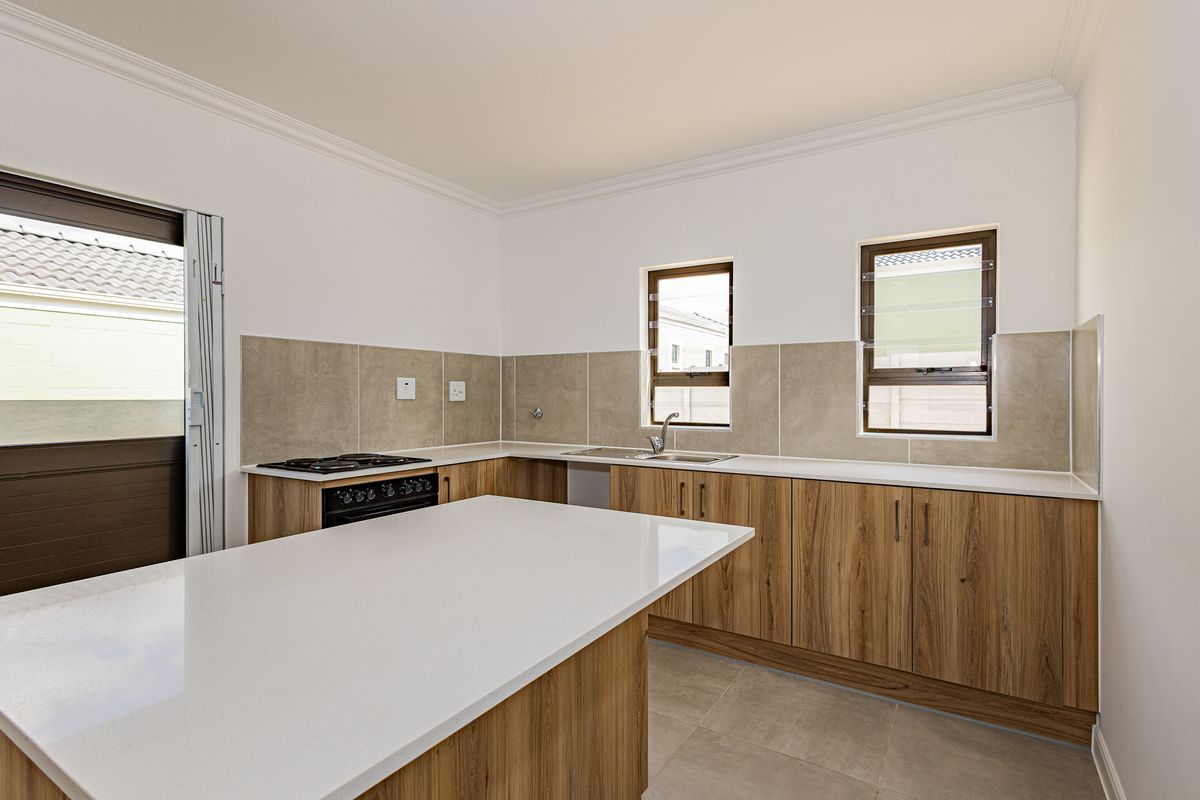 Modern kitchen featuring wood-finish cabinetry, stone countertops, a gas hob, and a tiled splashback, with direct access to the exterior.