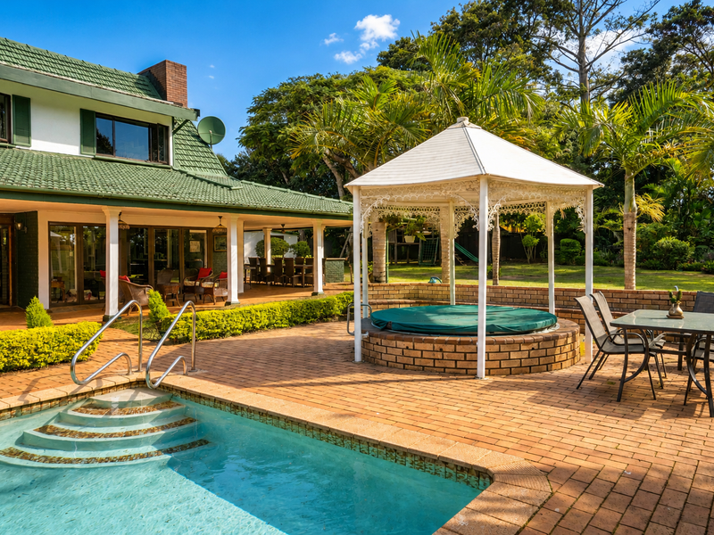 Outdoor entertainment area featuring a swimming pool, brick paved patio, covered veranda, and a gazebo with a built-in spa.