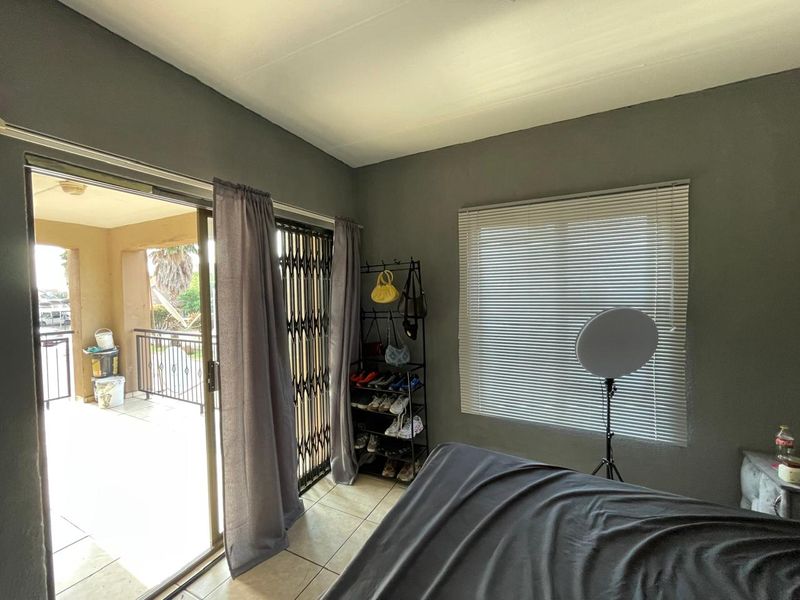 Bedroom featuring tiled flooring, venetian blinds, and a sliding glass door providing access to an outdoor balcony area.