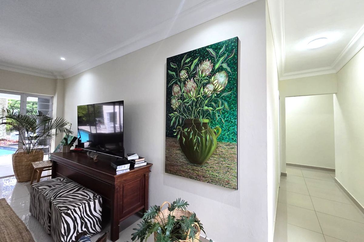 A bright living area featuring neutral tiled flooring, recessed lighting, and decorative cornice, with a sliding door providing access to the outdoor pool area.