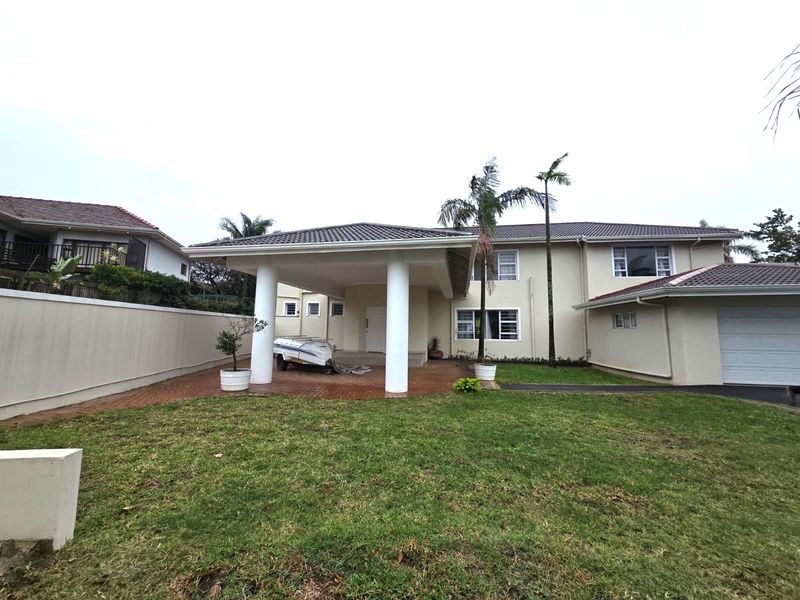Front view of a two-story residential property featuring a covered entrance portico, paved driveway, and attached garage.