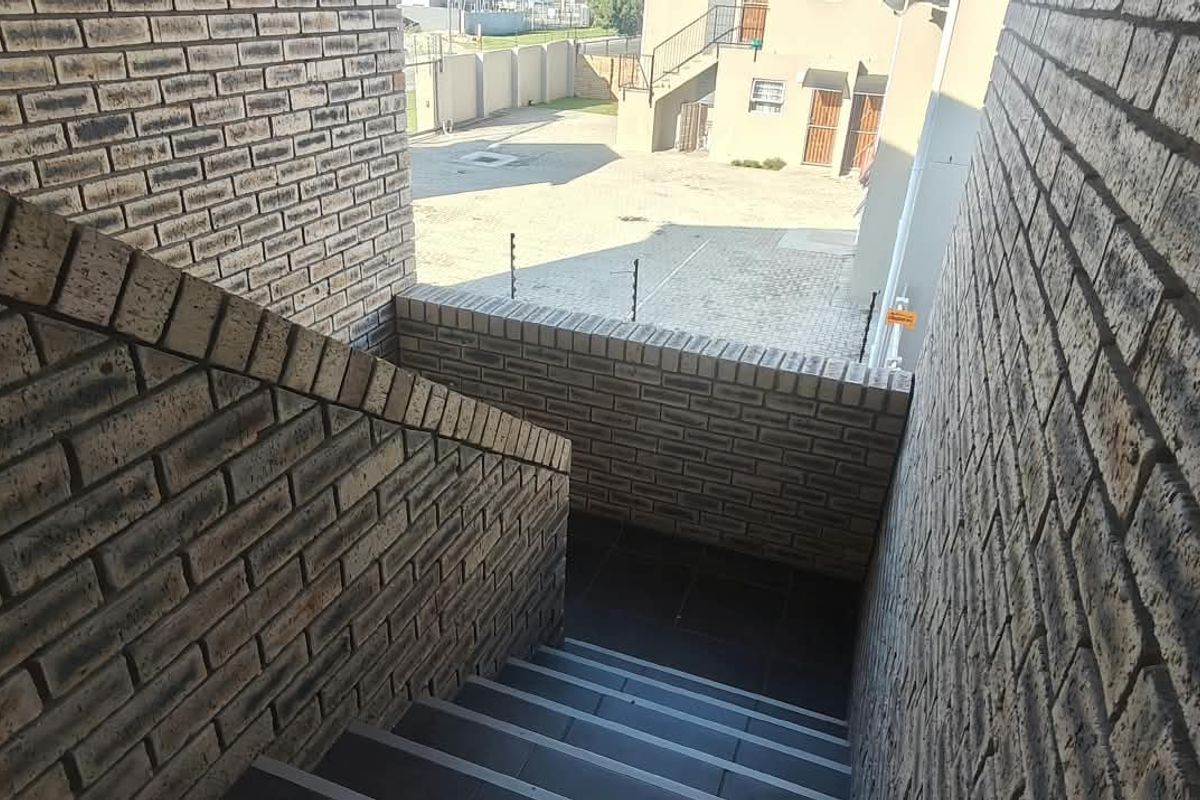 An outdoor brick staircase leading down to a paved courtyard area within an apartment complex.