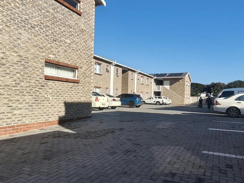 Exterior view of an apartment complex featuring a brick facade and a paved parking area for residents.
