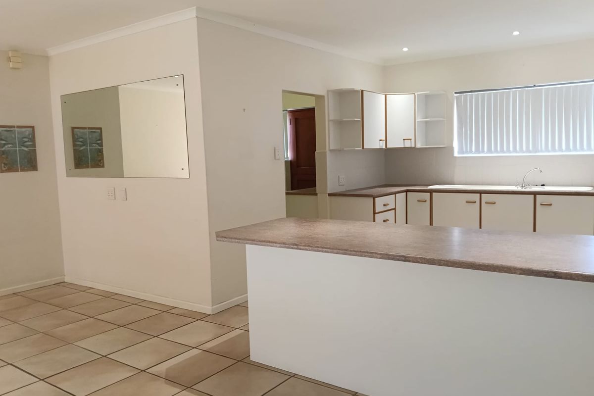 A functional, empty kitchen featuring laminate countertops, built-in cabinetry, and tiled flooring, offering a blank canvas for modern updates.