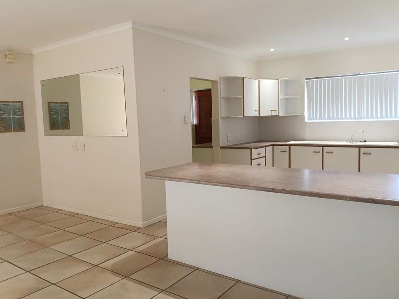A functional, empty kitchen featuring laminate countertops, built-in cabinetry, and tiled flooring, offering a blank canvas for modern updates.