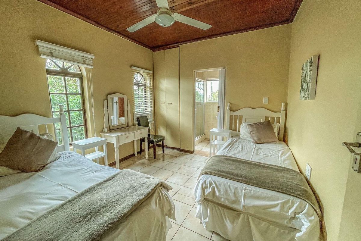 A bedroom featuring a timber-paneled ceiling, tiled flooring, built-in cupboards, and an en-suite bathroom access.
