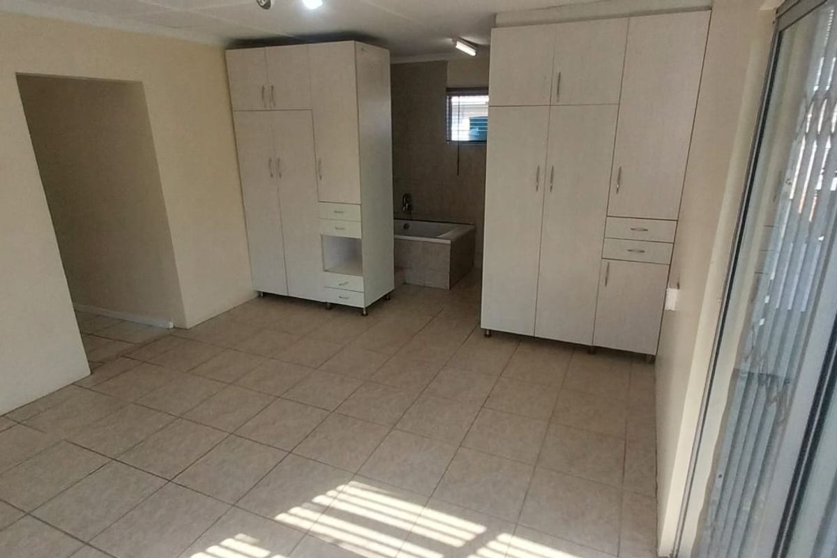 Spacious bedroom featuring built-in cupboards, tiled flooring, and a sliding door providing access to the exterior.