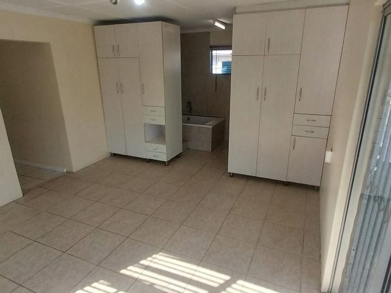 Spacious bedroom featuring built-in cupboards, tiled flooring, and a sliding door providing access to the exterior.