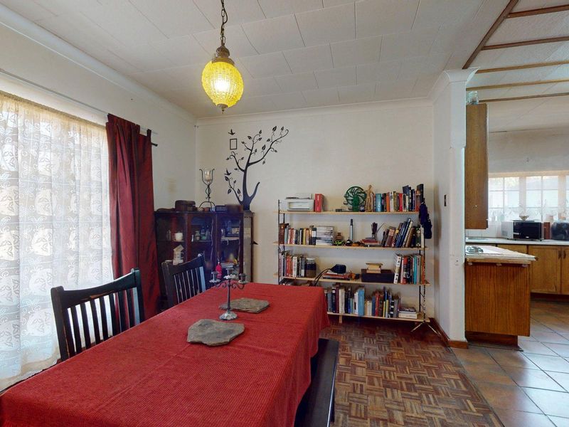 Open plan dining and kitchen area featuring parquet flooring, dated ceiling tiles, and traditional wooden cabinetry, offering potential for a modern renovation.