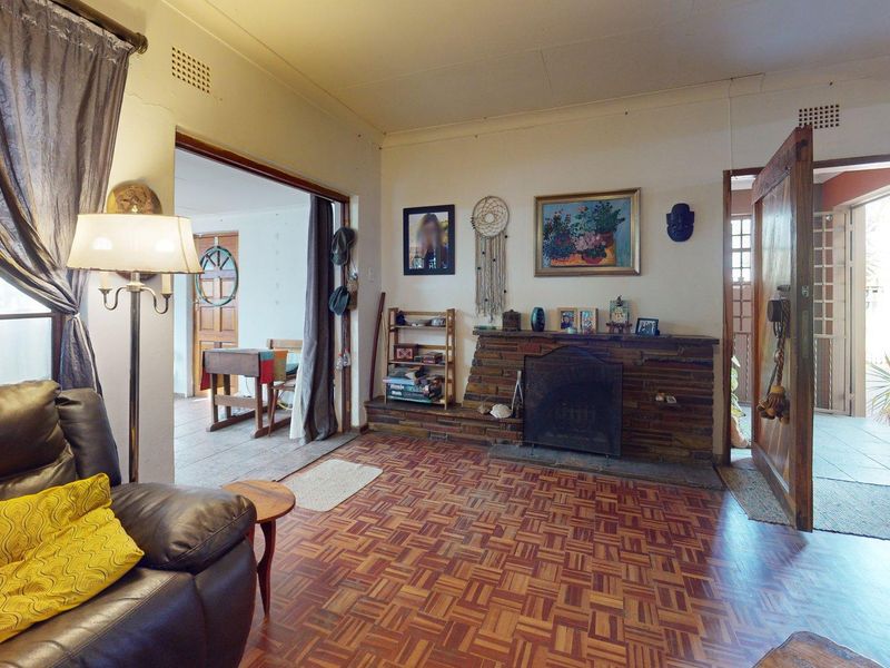 Living room featuring a traditional brick fireplace and classic parquet flooring, with direct access to adjacent living spaces.