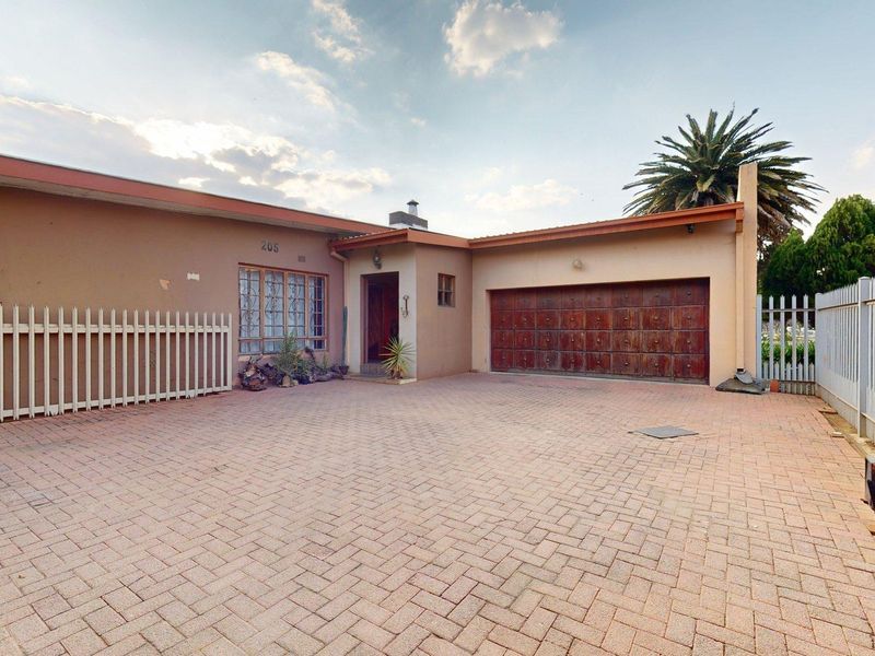 Front exterior view of the property featuring a paved driveway, secure fencing, and a single garage door.