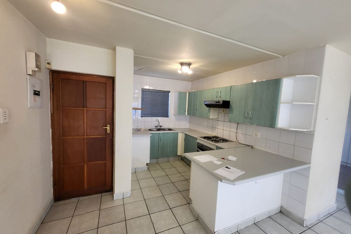A functional kitchen featuring built-in cabinetry, a tiled backsplash, and an electric hob, offering a blank canvas for modern renovation and design updates.