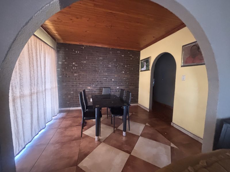Dining room featuring an exposed brick feature wall, timber ceiling, and arched architectural details, providing a distinct character to the living space.