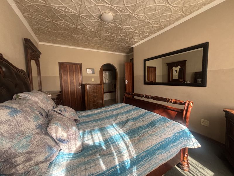 A bedroom featuring a unique textured ceiling, wooden door frames, and an arched entryway leading to an adjoining space.