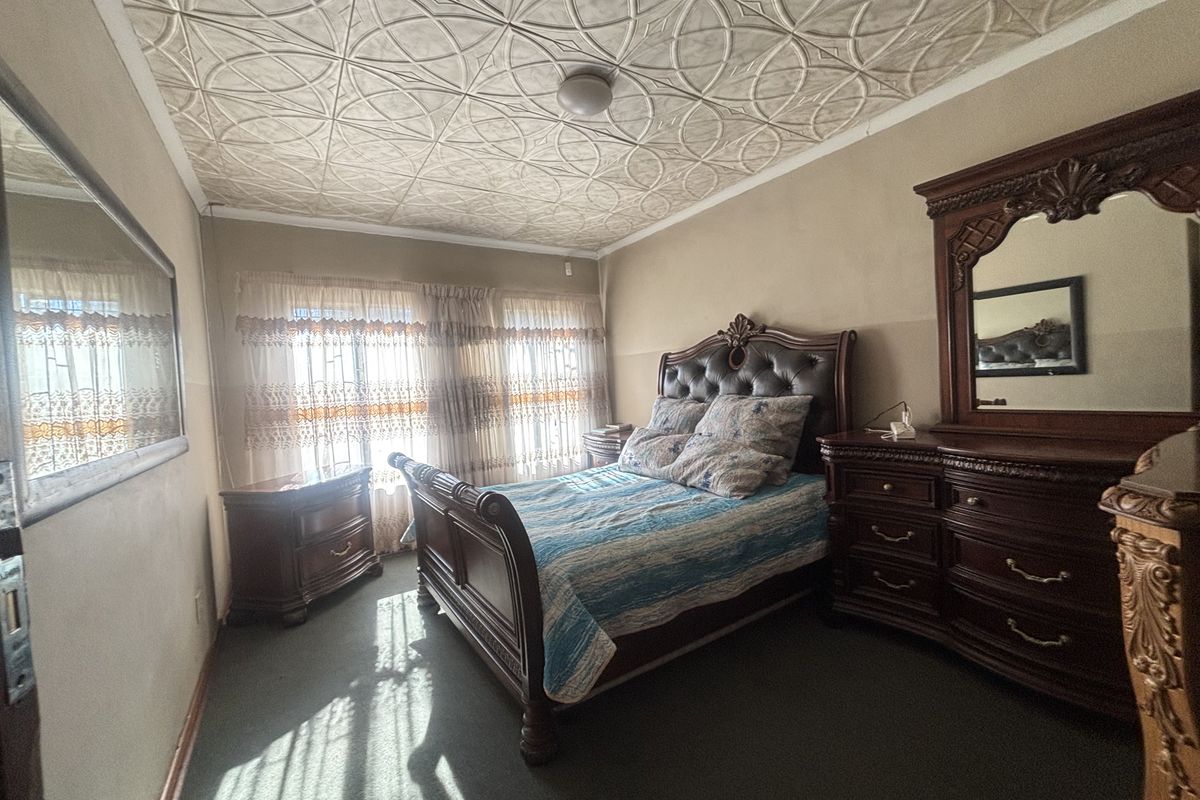 A bedroom featuring a unique decorative pressed metal ceiling and carpeted flooring, offering a classic aesthetic with potential for modern updates.